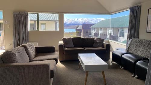 a living room with couches and a large window at Lake Tekapo Village Motel in Lake Tekapo