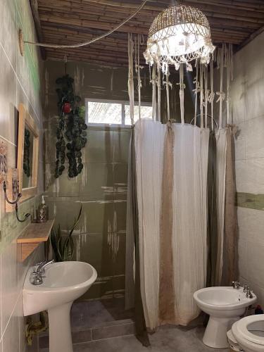 a bathroom with a sink and a toilet and a chandelier at Magia in Roldán