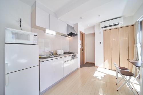 a kitchen with white appliances and a table and chairs at Yuzuki Dome Osaka Kujo in Osaka