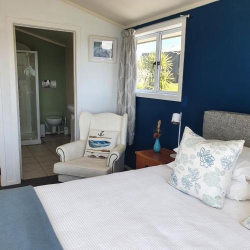 a bedroom with a bed and a chair and a window at Oneroa Bay View Apartment in Oneroa