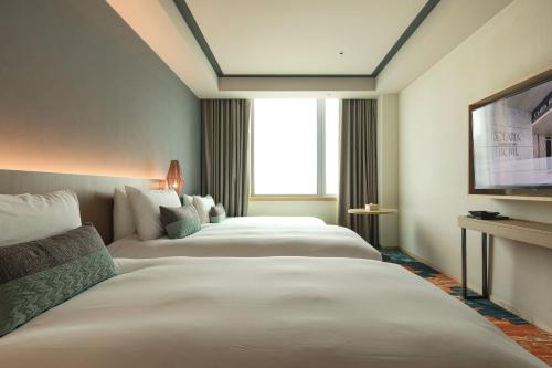 a hotel room with two beds and a television at Solaria Nishitetsu Hotel Taipei Ximen in Taipei