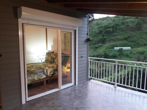 a room with a balcony with a bed and a window at L'Eden des Colibris in Vieux-Habitants