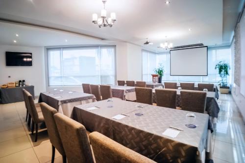 a conference room with tables and chairs and a projection screen at Wyndham Garden Guayaquil in Guayaquil
