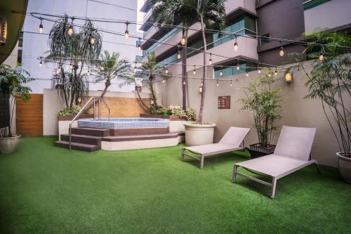 a courtyard with a hot tub and two chairs and plants at Wyndham Garden Guayaquil in Guayaquil