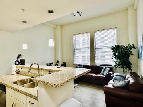 a kitchen and living room with a sink and a couch at Two Bedroom Game Day Suite with 100 Projector TV in Indianapolis