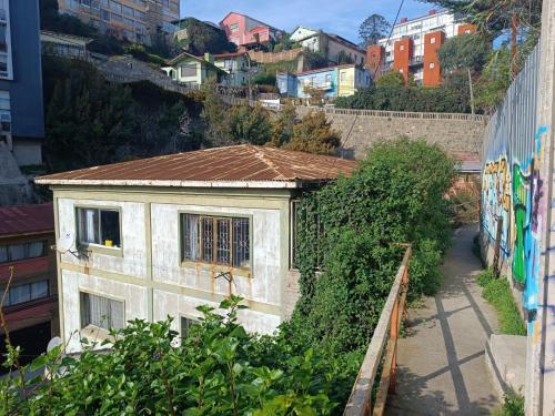 a small white building with a brown roof next to a street at Habitación en Valparaíso privada 1 in Valparaíso