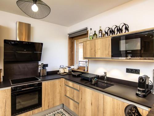 une cuisine avec des armoires en bois et un comptoir noir dans l'établissement Appartement de standing calme avec terrasse, espace bien-être et parking privé - FR-1-346-577, à Arc 1800