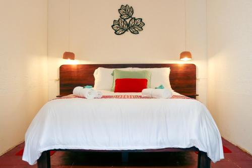 a bedroom with a large white bed with a red pillow at Villa Dulé in Antigua Guatemala
