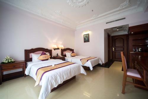 a bedroom with two beds and a desk at Regency Angkor Hotel in Siem Reap