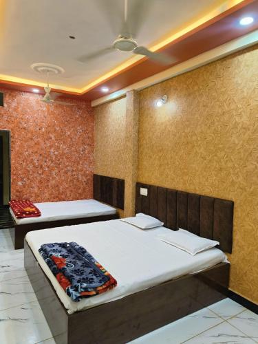 a bedroom with two beds and a wall at Kumkum guest house in Ujjain