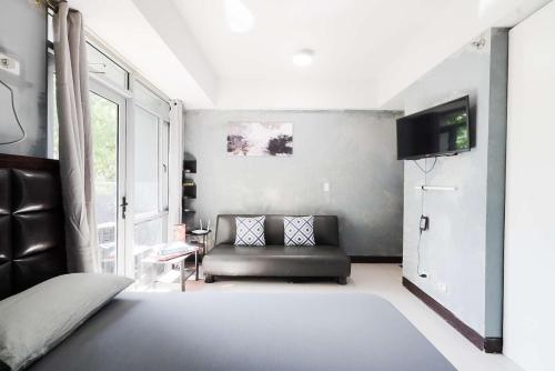 a living room with a couch and a tv at Cubao Manhattan Heights Residential Condo TA4N - Low Floor Studio with Pool & Balcony, 5 Mins Walk to Gateway Mall & Araneta Coliseum LRT MRT Cubao Quezon City - Staycations by SMS in Manila
