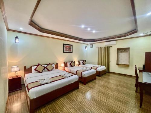 a hotel room with two beds and a television at Luang Prabang Xayana Hotel in Luang Prabang