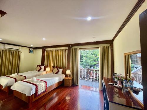 a bedroom with two beds and a balcony at Luang Prabang Xayana Hotel in Luang Prabang
