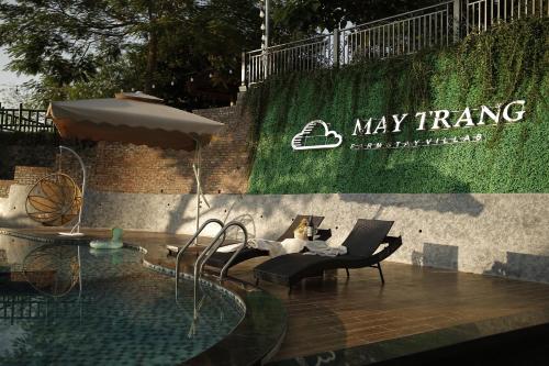 a pool with a table and chairs and an umbrella at Mây Trắng Villa and FarmStay in Ba Vì