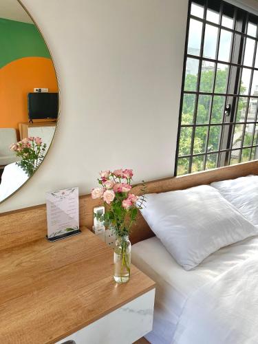 a bedroom with a vase of flowers on a table at POTA Hotel & Apartment in Da Nang