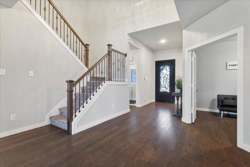 a staircase in a home with white walls and wood floors at The Aubrey Escape with Fenced Backyard in Aubrey