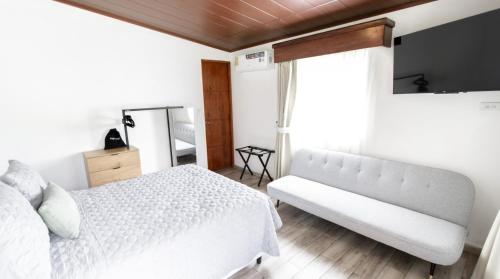 a bedroom with a white bed and a flat screen tv at Hotel Boutique Los Abetos in Boquete