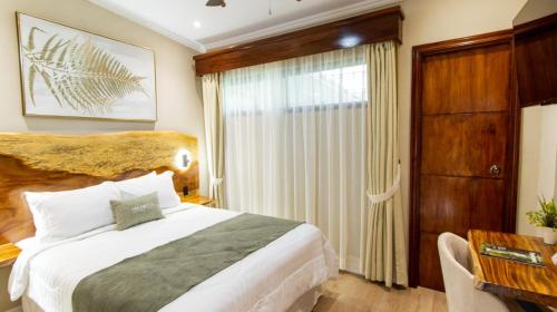 a bedroom with a bed and a desk and a window at Hotel Boutique Los Abetos in Boquete