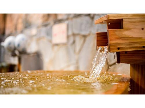 a stream of water coming out of a wooden water fountain at Kutsurogi no Yado Juraku - Vacation STAY 03506v in Tobe