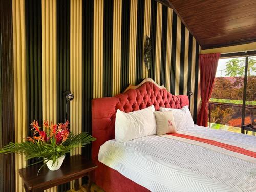 a bedroom with a large bed with a red headboard at Hotel Heliconias Nature Inn & Hot Springs in Fortuna