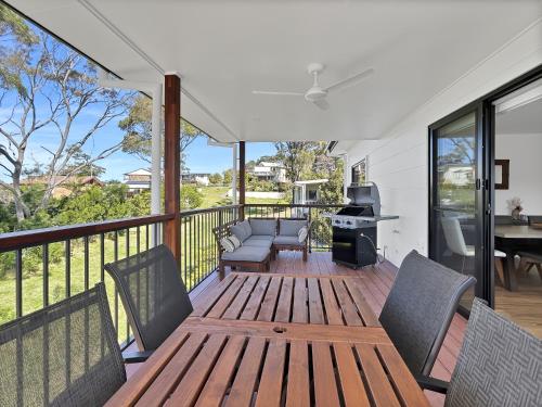 a patio with a wooden table and chairs on a deck at Chic 4-Bed with 3 Living Areas & Alfresco Dining in Malua Bay
