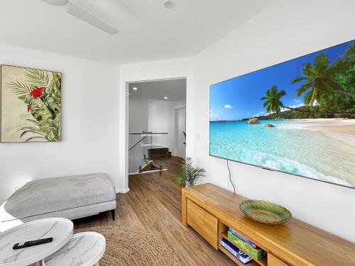 a living room with a large tv on the wall at Chic 4-Bed with 3 Living Areas & Alfresco Dining in Malua Bay