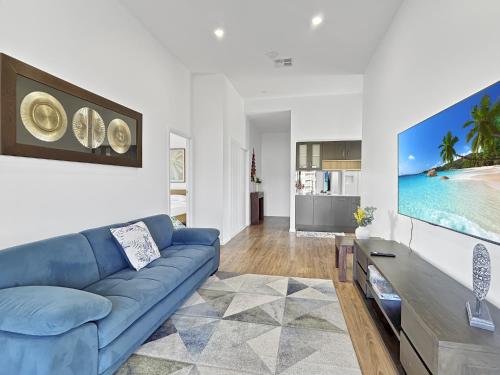 a living room with a blue couch and a tv at Chic 4-Bed with 3 Living Areas & Alfresco Dining in Malua Bay
