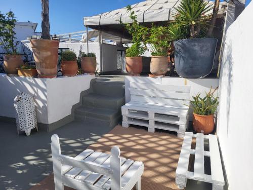 a patio with two white chairs and potted plants at Riad Dar Nawfal in Sale