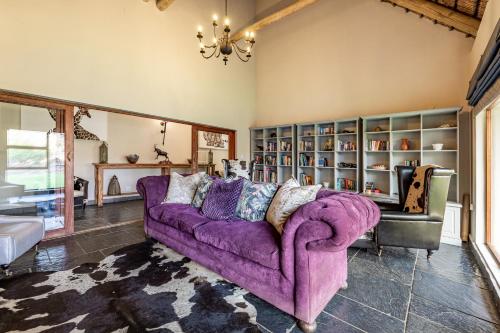 a living room with a purple couch and a book shelf at Kusudalweni Safari Lodge and Spa in Guernsey Nature Reserve