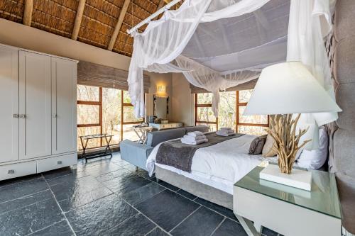 a bedroom with a bed and a table with a lamp at Kusudalweni Safari Lodge and Spa in Guernsey Nature Reserve