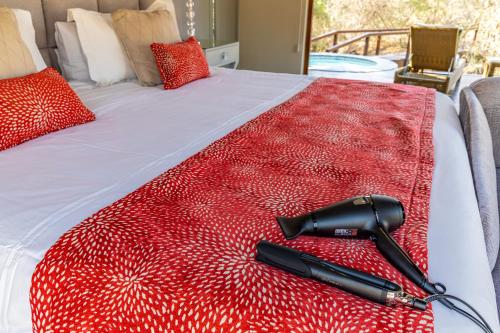a black gun laying on a red blanket on a bed at Kusudalweni Safari Lodge and Spa in Guernsey Nature Reserve