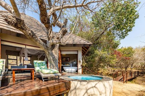 a patio with a tree and a table and chairs at Kusudalweni Safari Lodge and Spa in Guernsey Nature Reserve