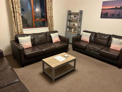 a living room with two leather couches and a coffee table at Bayview Self-Catering, Lerwick in Lerwick