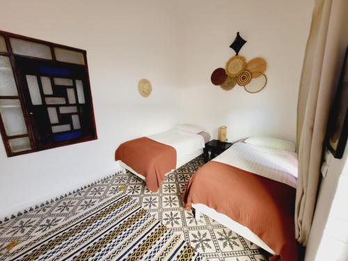 a bedroom with two beds and a window at Riad Dar Nawfal in Sale