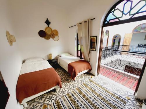 1 dormitorio con 2 camas y puerta a un balcón en Riad Dar Nawfal, en Sale