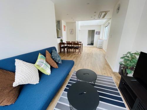 a living room with a blue couch and two stools at QUAYSIDE SAKURAGICHO 401 in Yokohama