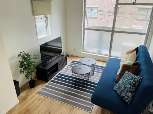 a living room with a blue couch and a tv at QUAYSIDE SAKURAGICHO 401 in Yokohama