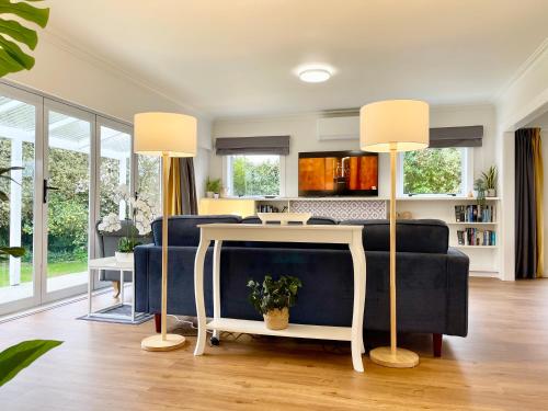 a living room with a blue couch and two lamps at Quiet, private and 5-bedroom holiday house in Hamilton