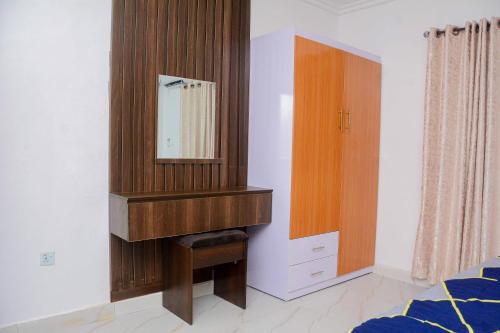 a bedroom with a wooden dresser and a mirror at Ruby Apartment in Eregun