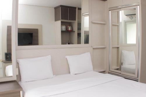a white bed with white pillows in a room at Cozy and Warm Studio at Grand Sentraland Karawang Apartment By Travelio in Karawang