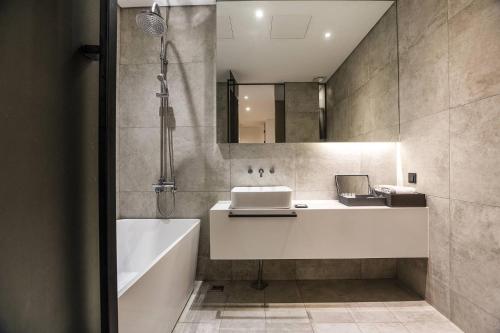 a bathroom with a tub and a sink and a bath tub at Hotel The Designers Cheongnyangni in Seoul