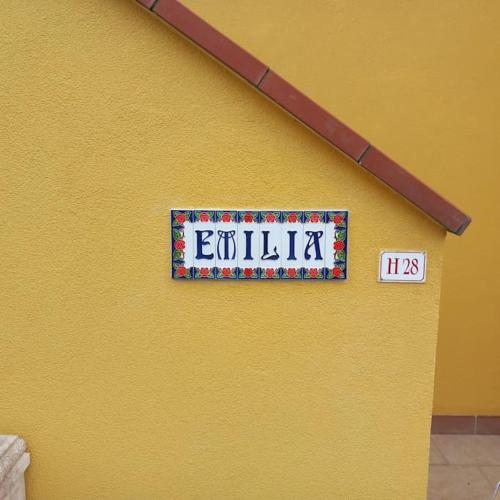 a sign on the side of a yellow wall at Villa Emilia in Eraclea Mare
