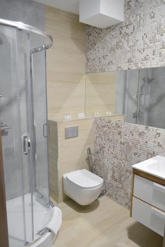 a bathroom with a toilet and a glass shower at Noclegi Zakład Aktywności Zawodowej w Świerzawie in Świerzawa