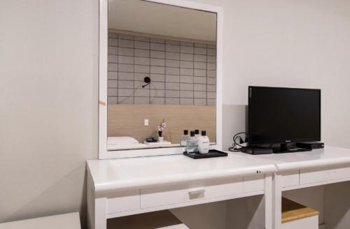 a white desk with a television and a mirror at Apple Hotel in Jeju