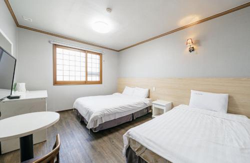 a hotel room with two beds and a table at Apple Hotel in Jeju