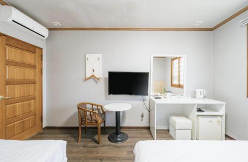 a bedroom with a desk and a table and a tv at Apple Hotel in Jeju