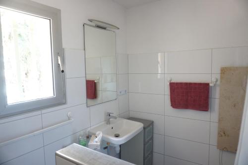 une salle de bain blanche avec un lavabo et une fenêtre dans l'établissement Presqu`ile de Giens, à Hyères