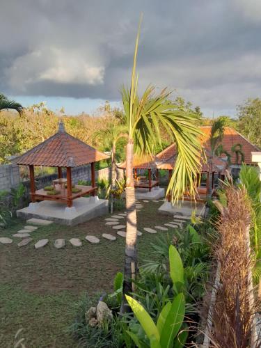 a resort with a palm tree and a gazebo at The Seaglass Villas Bingin in Uluwatu