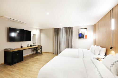 a hotel room with two beds and a flat screen tv at Seosan Mari Hotel in Seosan