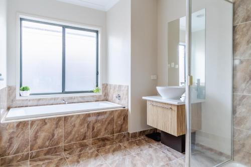 a bathroom with a tub and a sink and a window at Point Cook Spacious Maison in Point Cook